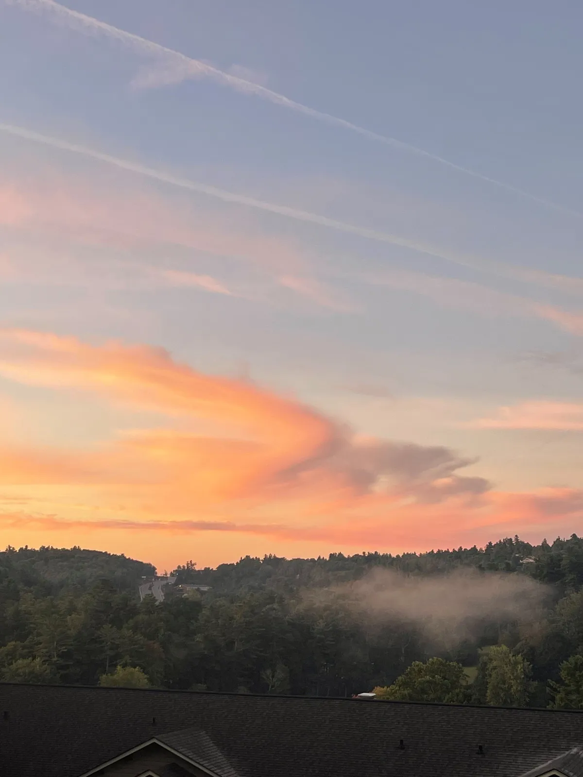 A sweeping vista of colorful sky, mist drifting through trees, and distant hills. The landscape is tranquil and romantic, ideal for nature walks, sunset watching, or quiet reflection. The scene captures the atmosphere of the surrounding region at dusk.