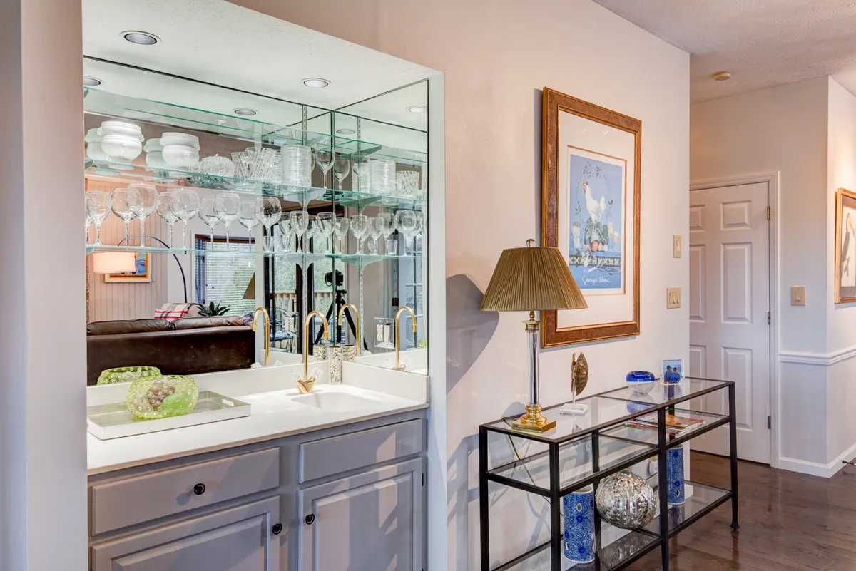 An elegant bar area featuring glassware, a decorative lamp, and framed artwork. The inviting ambiance suggests a perfect spot to unwind with a drink after a day out.